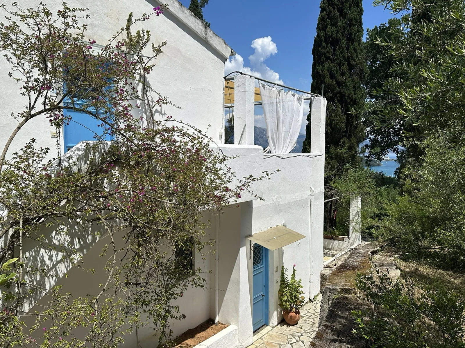 Extérieur de la maison avec bougainvillier et porte bleue